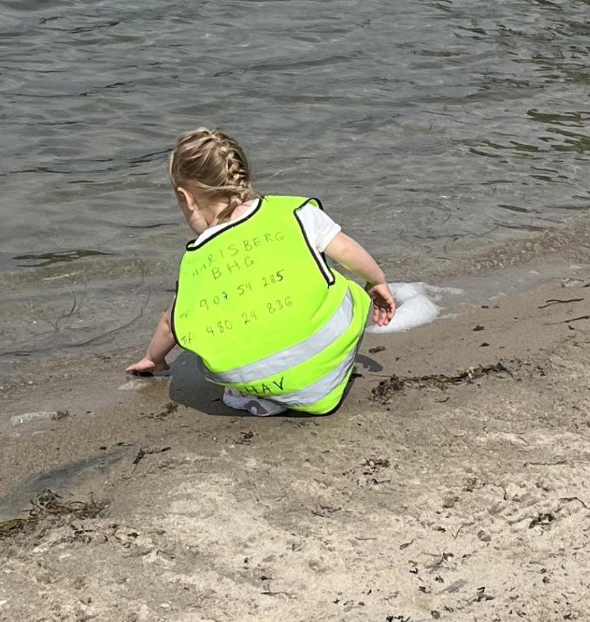 Jente som står på stranda i vannkanten - Klikk for stort bilde