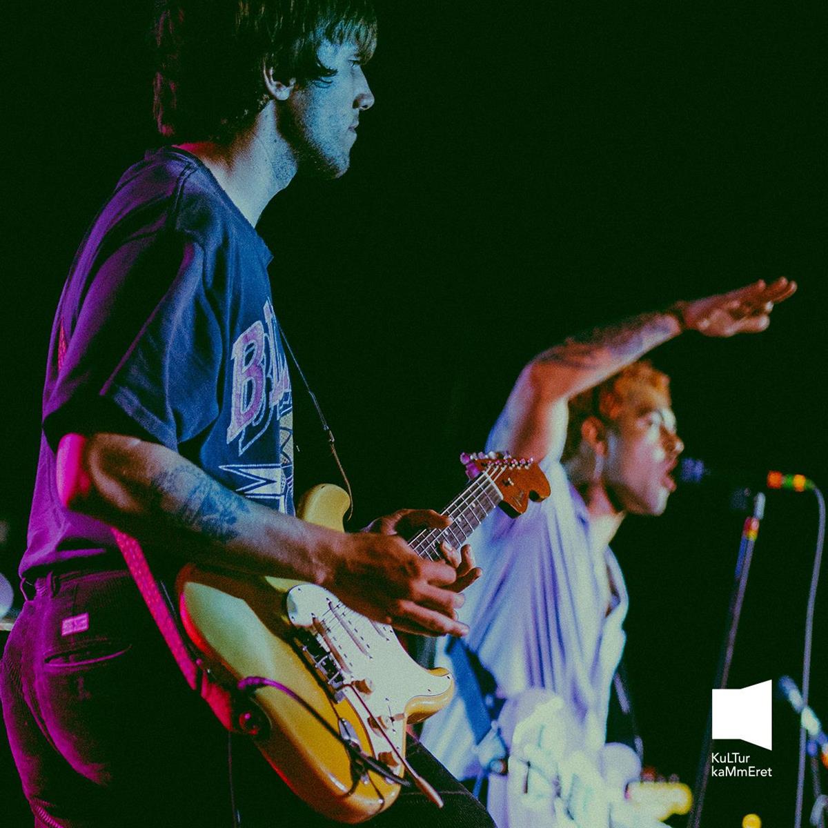 To menn som spiller gitar og synger på scenen