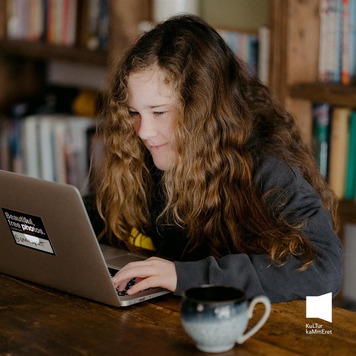 En ung jente som sitter foran en laptop og gjør lekser