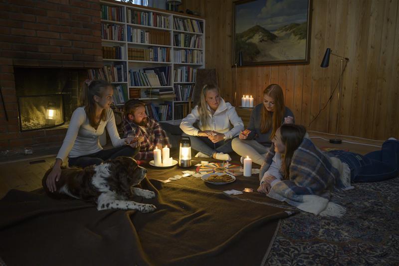 Familie sitter rundt noen stearinlys i en stue